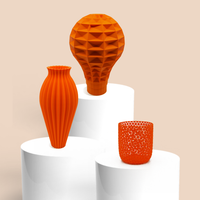 Three orange 3D printed vases on white cylindrical stands against a beige background - BEDROCK 3D Standard Filaments